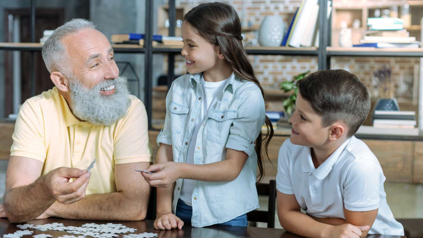 A grandparent and grandchildren bonding over a puzzle, embodying the spirit of the Grandparents Day Tea event.